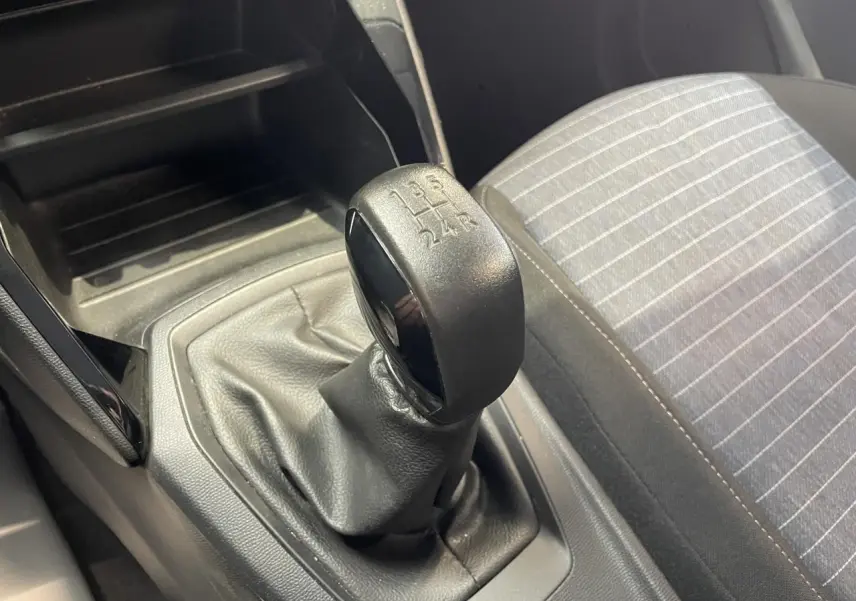 Gros plan sur le levier de vitesses manuel noir et la sellerie tissu gris à rayures de la Peugeot 208.