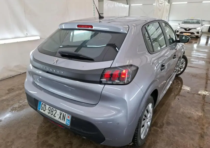 Vue 3/4 arrière droite d'une Peugeot 208 gris Artense avec feux arrière allumés en intérieur.