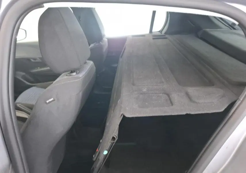 Vue intérieure arrière droite d'une Peugeot 208 gris Artense avec banquette rabattue et cache-bagages noir.