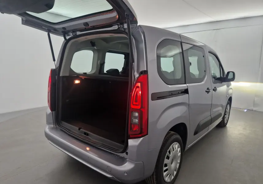 Vue 3/4 arrière droite d'un Opel Combo Life gris Artense avec hayon ouvert et intérieur spacieux visible.