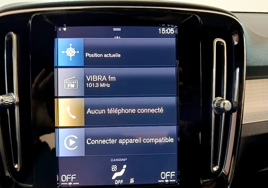 Écran tactile central affichant la radio et la connexion téléphone dans le tableau de bord noir du Volvo XC40 gris clair.