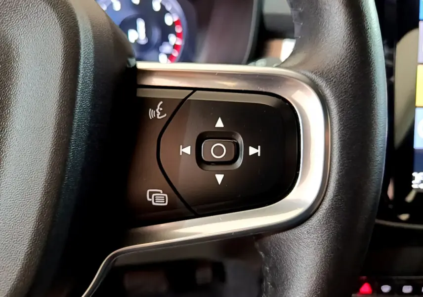 Gros plan sur les commandes multifonctions du volant en cuir noir du Volvo XC40 T2 gris clair, vue intérieure côté gauche.