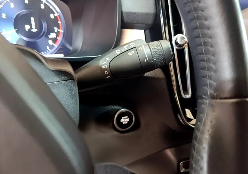 Gros plan sur la manette d'essuie-glace et le bouton démarrage du tableau de bord d'un Volvo XC40 gris clair.