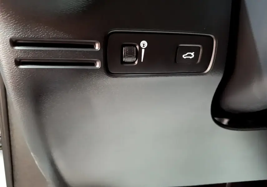 Détail intérieur montrant les commandes d'ouverture du coffre et réglage du volant sur Volvo XC40 T2 gris clair.