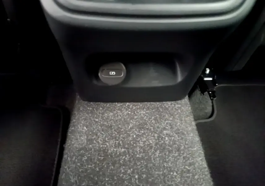 Prise 12V et espace de rangement sous la console centrale arrière du Volvo XC40 T2 gris clair, vue rapprochée du plancher.