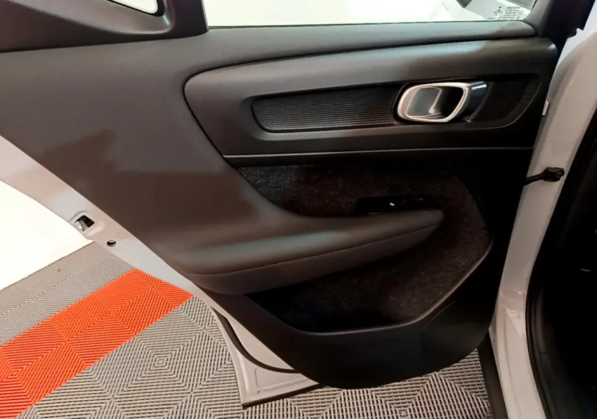 Porte arrière droite ouverte du Volvo XC40 gris clair, montrant le panneau intérieur noir avec poignée chromée.