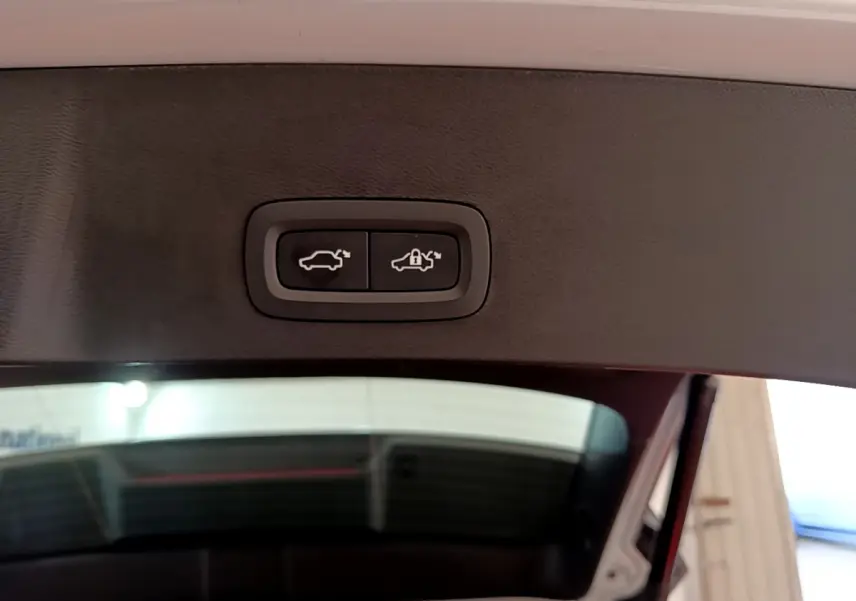 Gros plan sur les boutons d'ouverture et verrouillage du coffre, intérieur noir du hayon du Volvo XC40 gris clair.