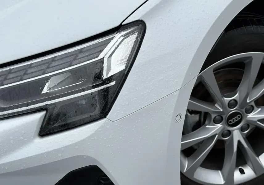 Gros plan sur l'avant droit de l'Audi A3 Berline blanc Arkona, mettant en valeur le phare LED et la jante alliage 17 pouces.