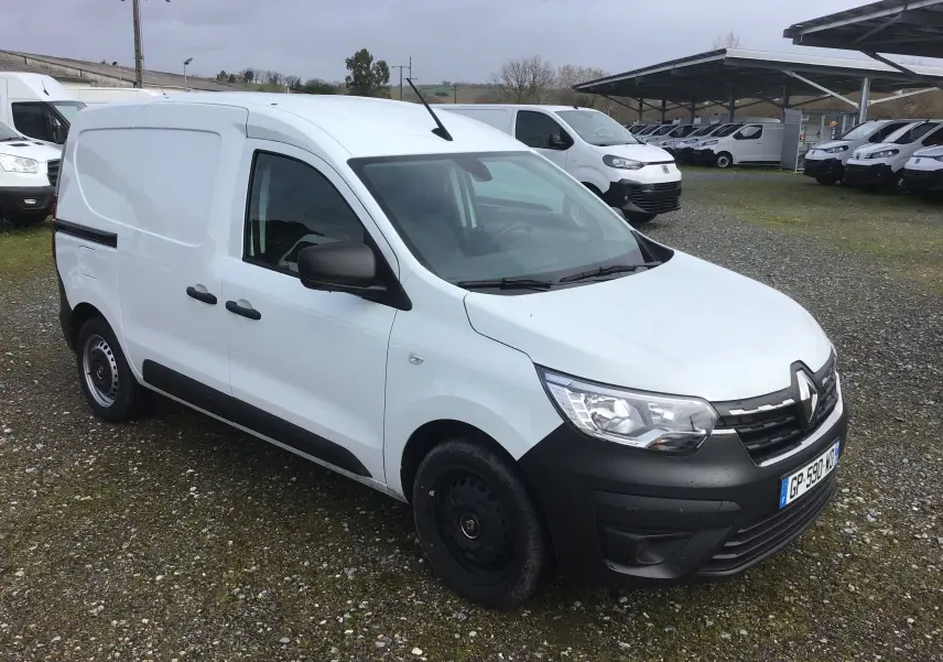 Renault Express Van blanc en 3/4 avant droit, avec pare-chocs noirs et jantes acier noires, stationné sur sol gravillonné.