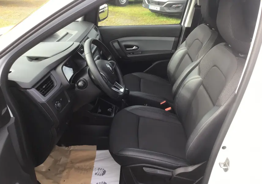 Vue intérieure côté conducteur du Renault Express Van blanc 2023, montrant les sièges noirs et le tableau de bord épuré.