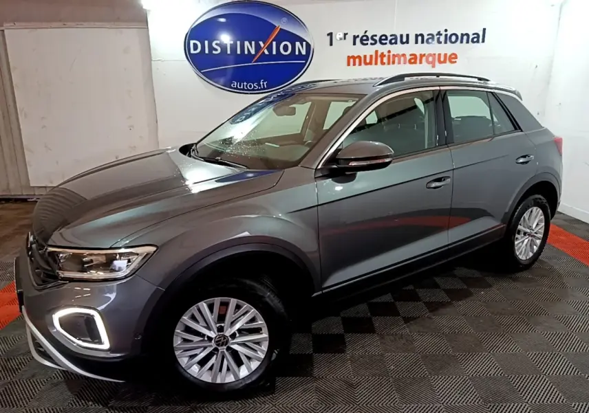 Vue 3/4 avant droit d'un Volkswagen T-Roc gris foncé avec feux LED et jantes alliage en intérieur showroom.