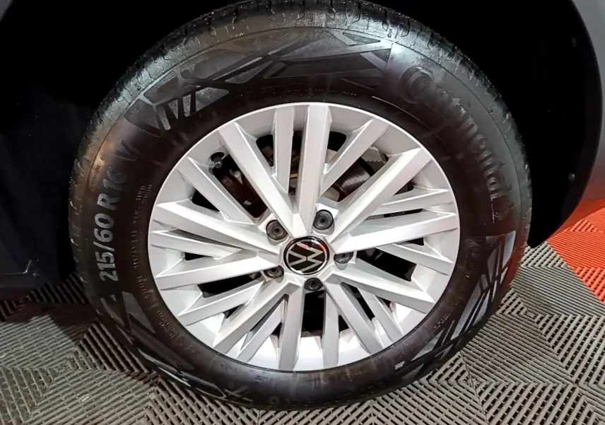 Gros plan sur la roue avant droite du Volkswagen T-Roc gris foncé, jante alliage argentée avec logo VW central.