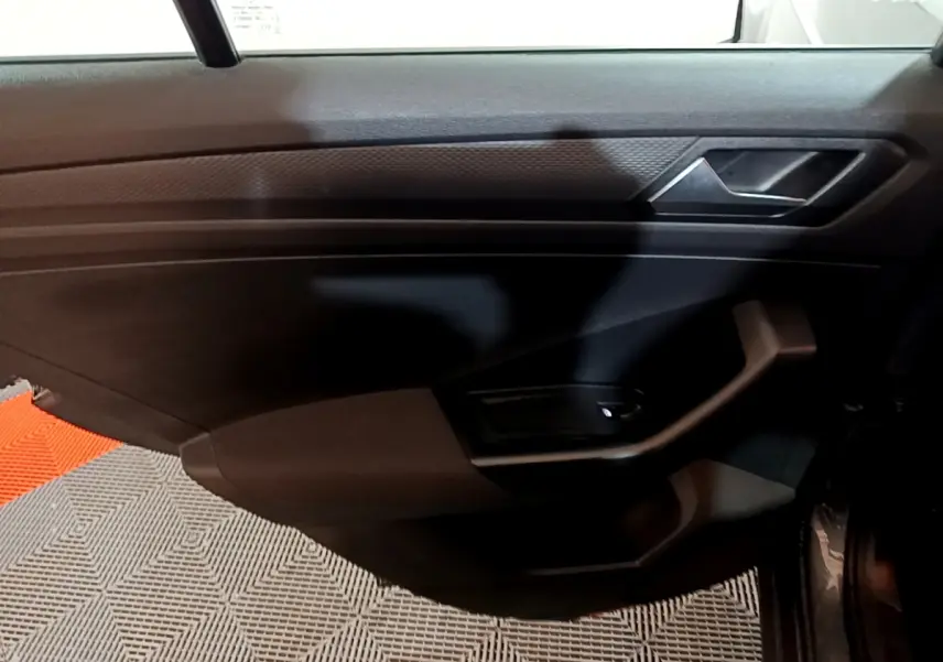 Vue intérieure du panneau de porte avant gauche du Volkswagen T-Roc gris foncé, avec poignée et commande de vitre.