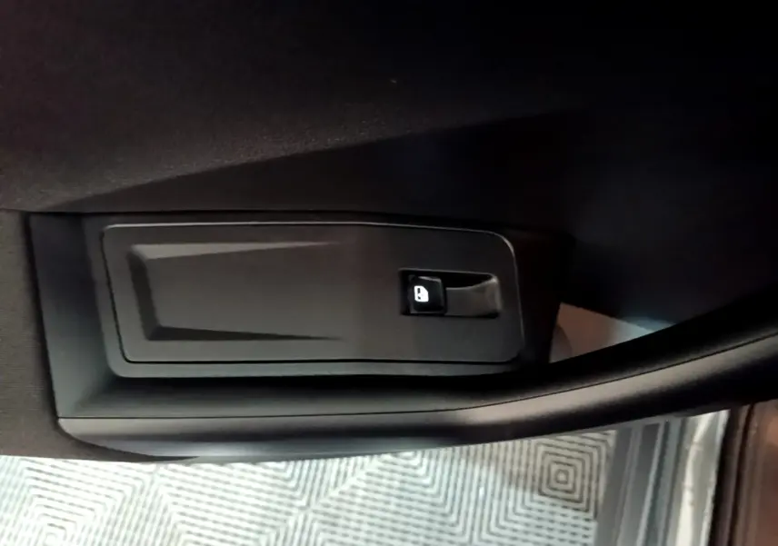 Détail de la commande d'ouverture de coffre sur la porte intérieure d'un Volkswagen T-Roc gris foncé.