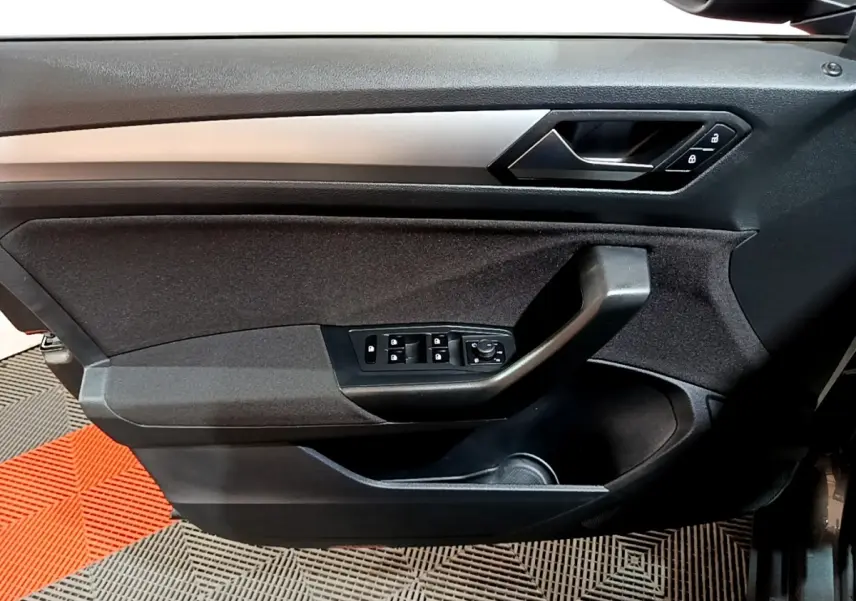Vue intérieure côté gauche de la porte avant grise du Volkswagen T-Roc 2022 avec commandes de vitres et poignée noire.