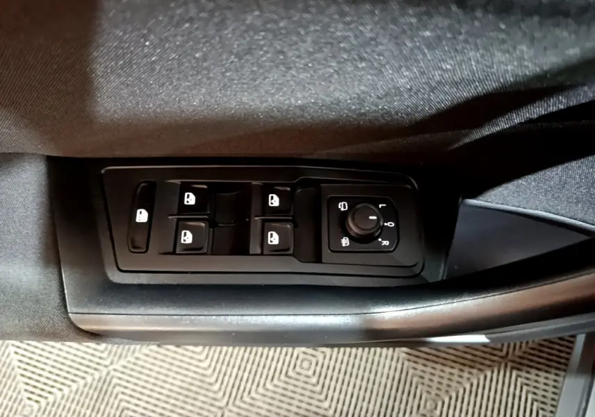 Vue rapprochée des commandes de lève-vitres et réglage des rétroviseurs côté conducteur d’un Volkswagen T-Roc gris foncé.