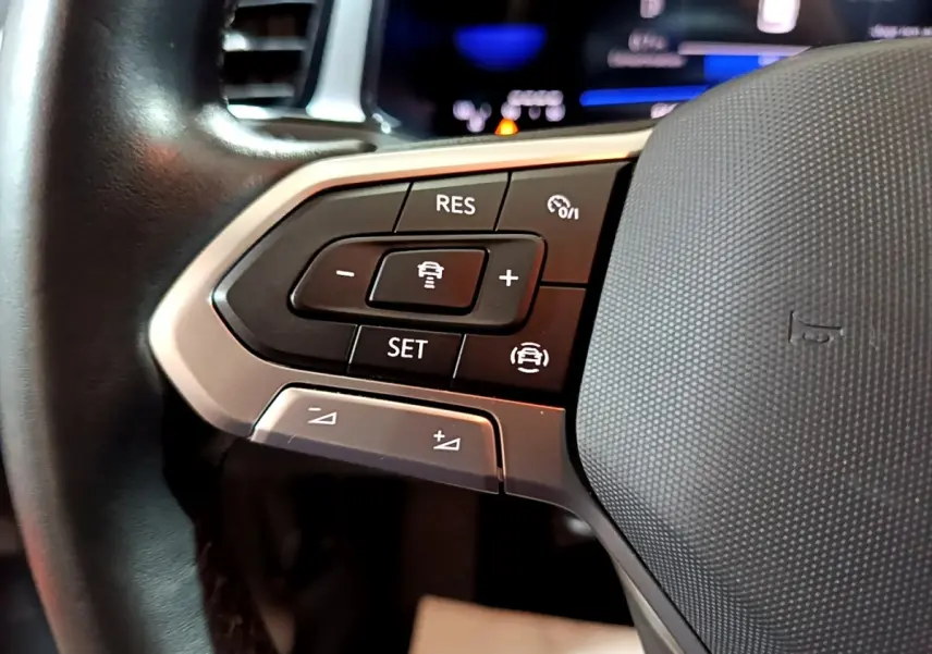 Gros plan sur les commandes de régulateur de vitesse au volant cuir du Volkswagen T-Roc gris foncé, version 2022.