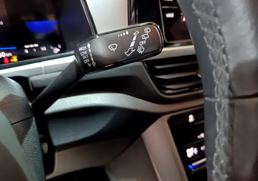 Gros plan sur la manette d’essuie-glace à gauche du volant cuir dans l’habitacle du Volkswagen T-Roc gris foncé.