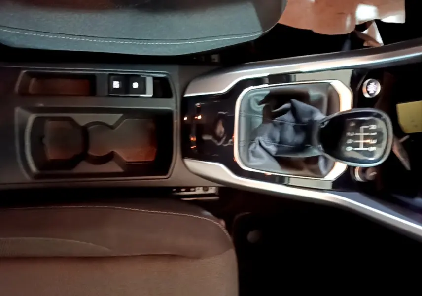 Vue plongeante sur la console centrale d’un Volkswagen T-Roc 2022 avec levier de vitesse manuel et rangement noir.