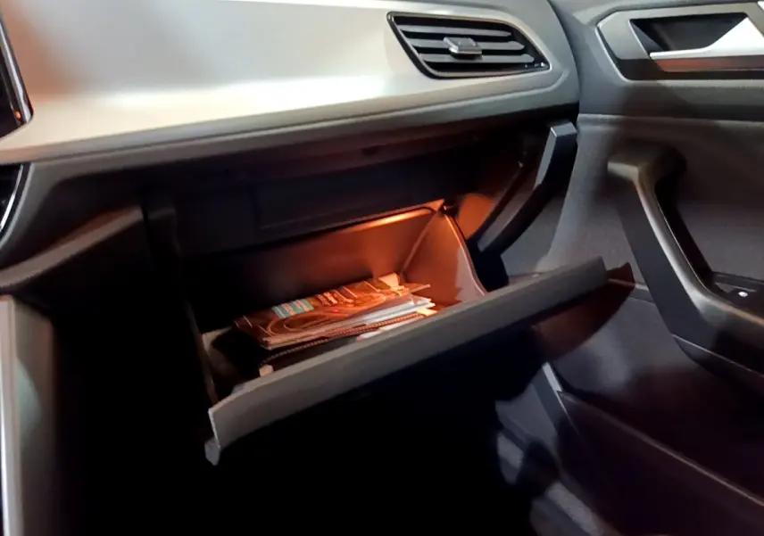 Gant de boîte à gants ouvert avec éclairage intérieur dans Volkswagen T-Roc gris foncé, vue côté passager.