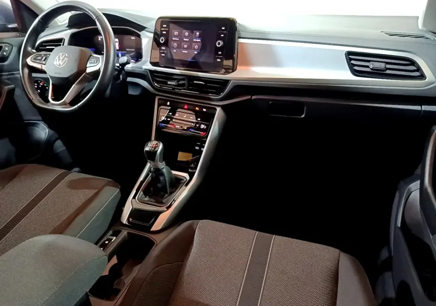 Intérieur Volkswagen T-Roc 1.0 TSI 2022 vu de face, tableau de bord noir avec écran tactile et levier de vitesse manuel.