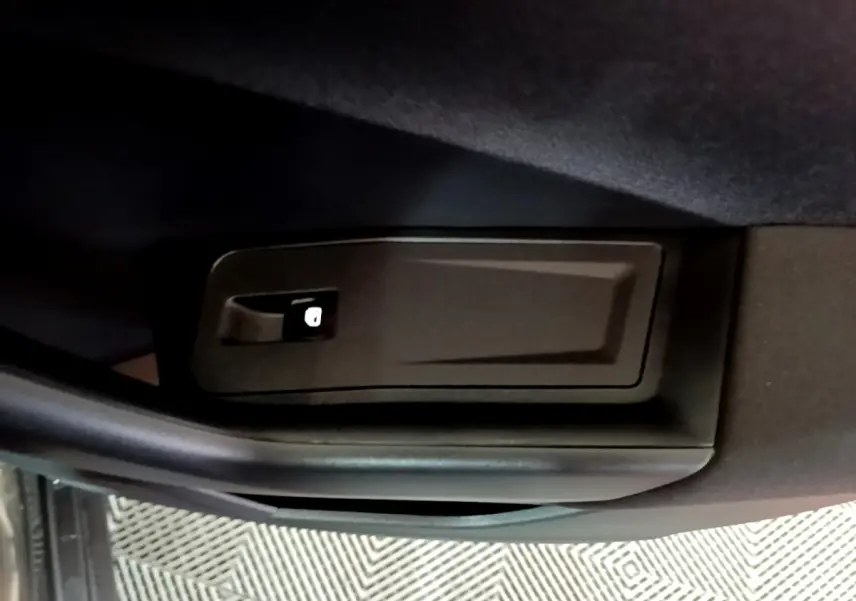 Détail du verrouillage intérieur de porte noir dans un Volkswagen T-Roc gris foncé, vue rapprochée.