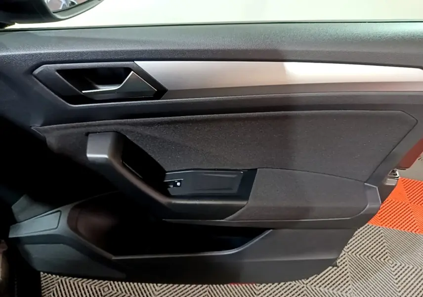 Détail de la porte intérieure côté conducteur du Volkswagen T-Roc gris foncé, avec poignée et insert argenté.