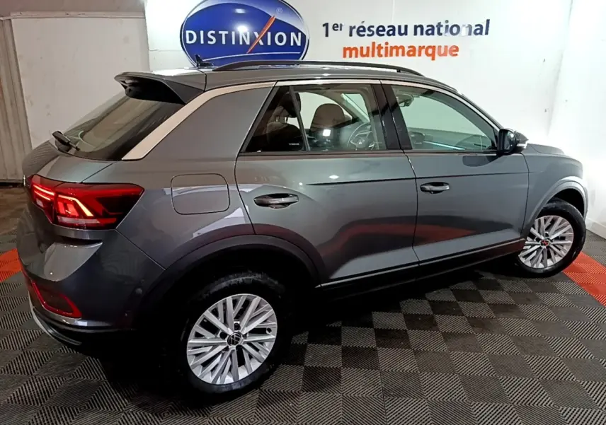 Volkswagen T-Roc gris foncé vue 3/4 arrière droit, feux arrière allumés et jantes alliage visibles.