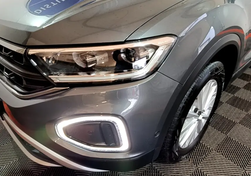 Gros plan sur l'avant droit du Volkswagen T-Roc gris foncé, mettant en valeur le phare LED et la roue.