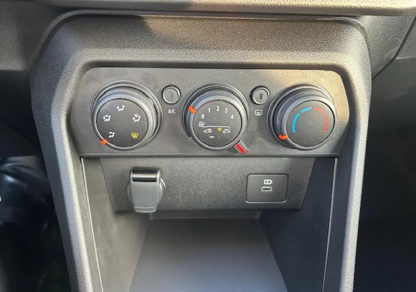 Gros plan sur les commandes de climatisation et prises USB du tableau de bord de la Dacia Sandero Stepway blanche.