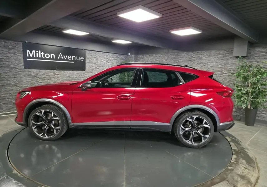 Vue de profil côté gauche d'un CUPRA Formentor 2024 rouge Désir avec jantes alliage noires et soubassements contrastants.
