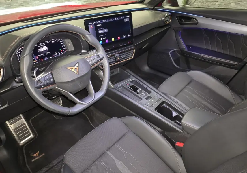 Vue intérieure côté conducteur du CUPRA Formentor 1.4 e-Hybrid 2024, avec volant sport, écran tactile et ambiance lumineuse violette.