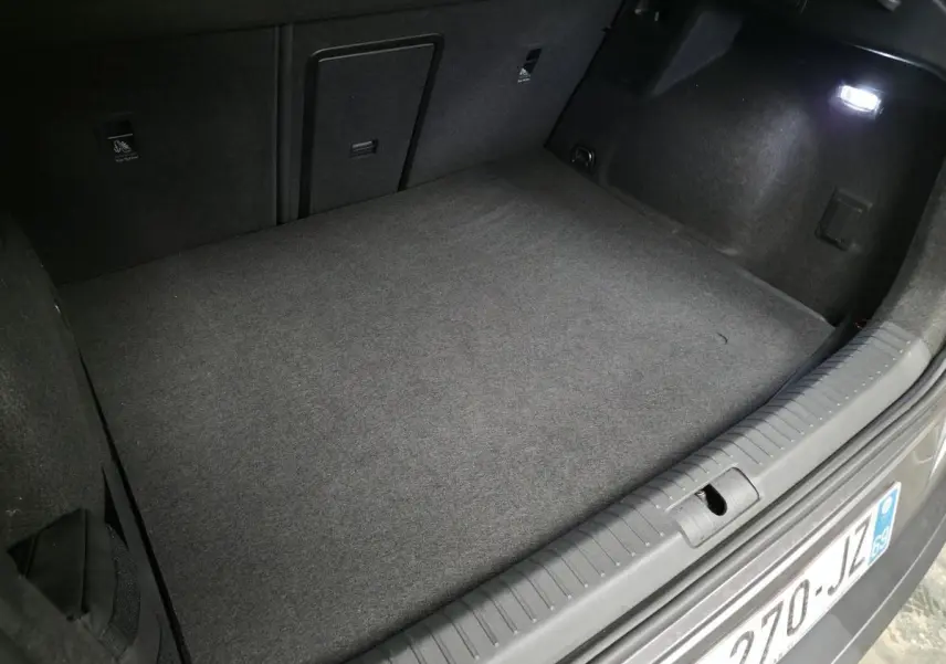 Coffre ouvert vu de l'arrière d'une CUPRA Formentor rouge, espace de chargement vide et éclairage intérieur allumé.