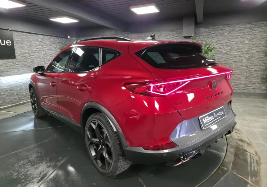 Vue 3/4 arrière droite du CUPRA Formentor rouge avec bandeau lumineux arrière et jantes alliage noires.
