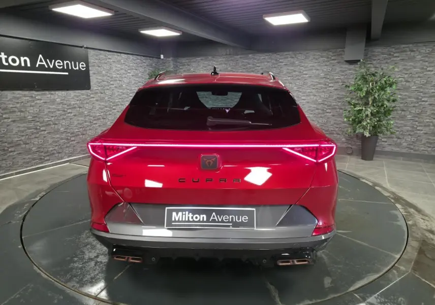 Vue arrière d'une CUPRA Formentor rouge avec bandeau LED Infinite Light et double sortie d'échappement copper stylisée.