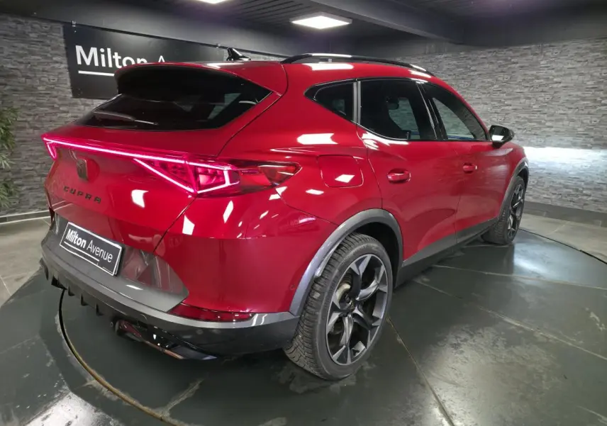 Vue 3/4 arrière droite du CUPRA Formentor rouge Désir 2024 avec bandeau LED arrière et jantes alliage noires.