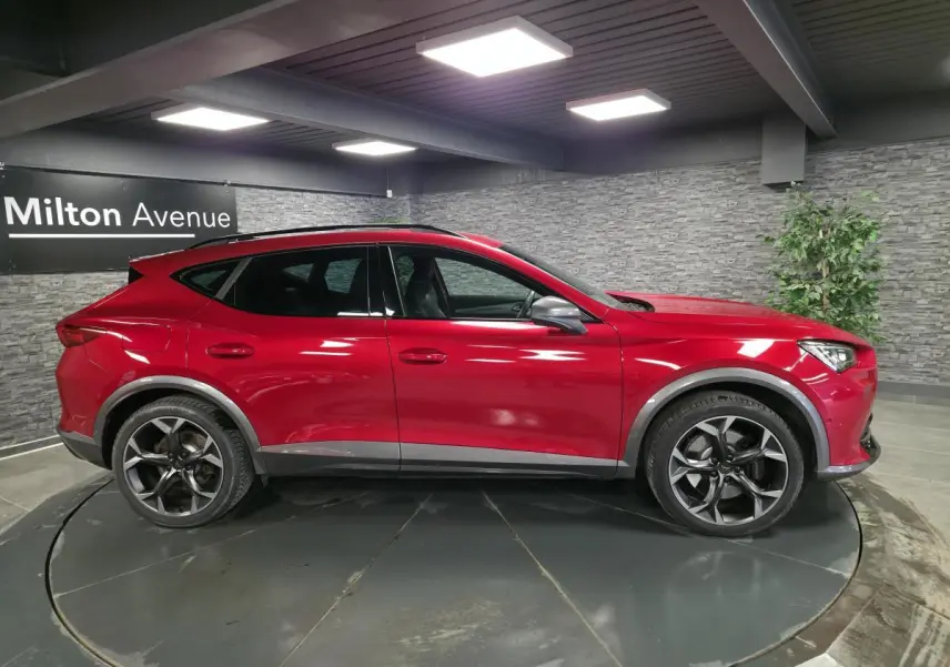 Vue de profil côté gauche du CUPRA Formentor 1.4 e-Hybrid rouge Désir avec jantes alliage 19 pouces et toit noir.