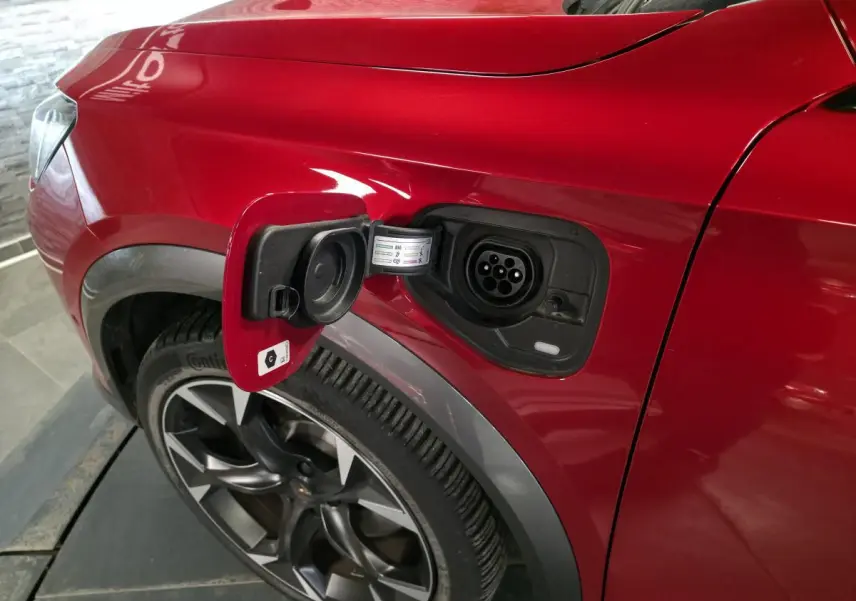 Vue rapprochée du côté gauche arrière du CUPRA Formentor rouge avec prise de recharge hybride ouverte et jante alliage 19 pouces.