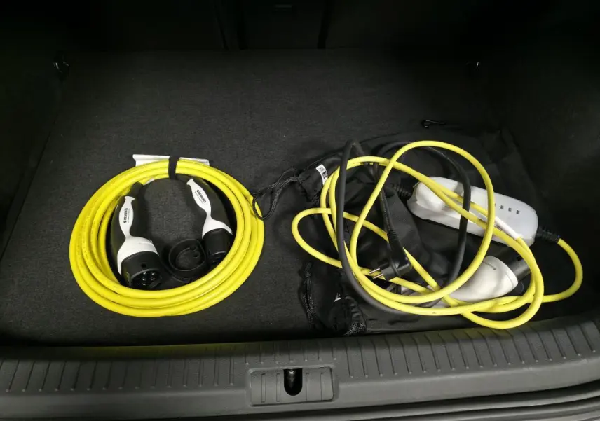 Vue du coffre d'un CUPRA Formentor rouge 2024 montrant les câbles de recharge jaune et noir rangés.