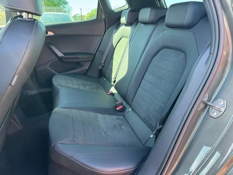 Vue intérieure côté droit des sièges arrière en tissu gris et cuir noir du SEAT Arona 2025, porte ouverte.