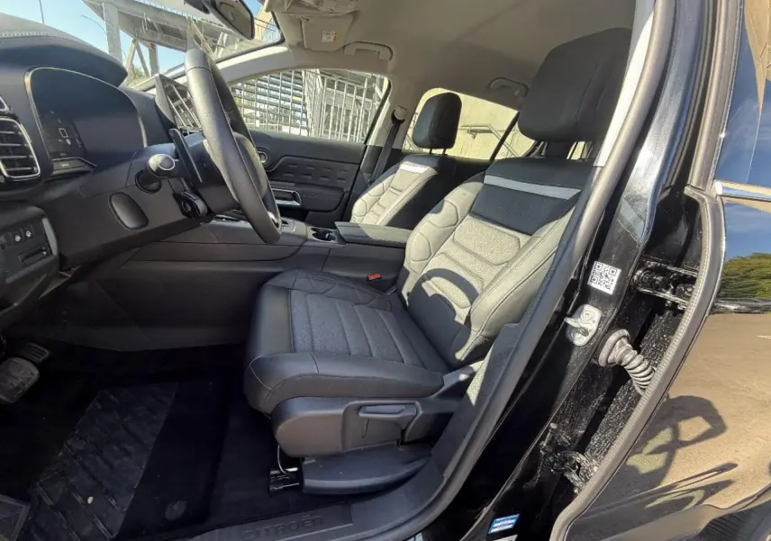 Vue intérieure côté conducteur du Citroën C5 Aircross 2024 artense, montrant les sièges et le tableau de bord noirs.