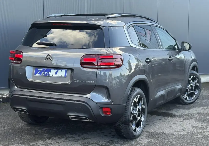 Vue 3/4 arrière droite d'un Citroën C5 Aircross gris Platinium avec jantes diamantées et toit ouvrant panoramique.