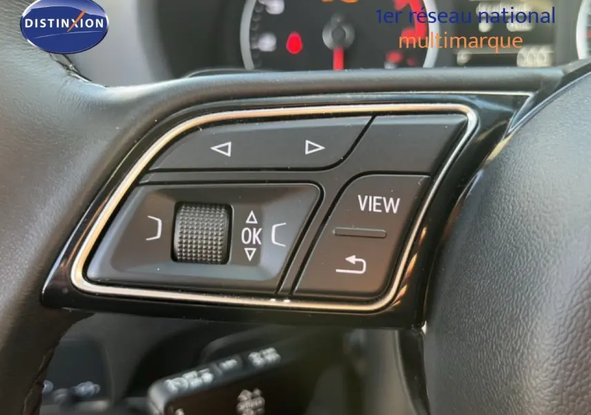 Gros plan sur les commandes au volant de l'Audi Q2 35 TFSI S-Line, avec boutons multifonctions et molette tactile.