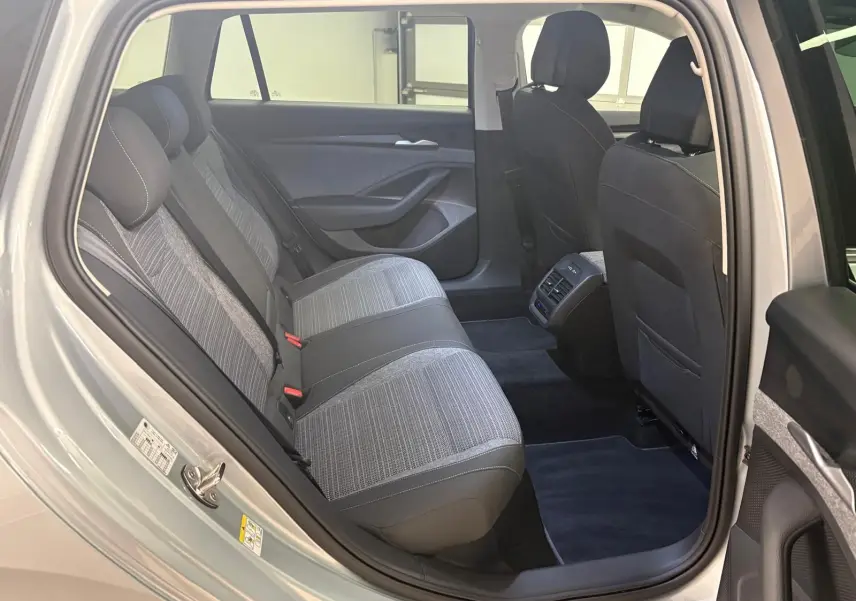 Vue intérieure côté arrière droit d'un Skoda Superb Combi gris argent 2025, montrant les sièges arrière et les aérations centrales.