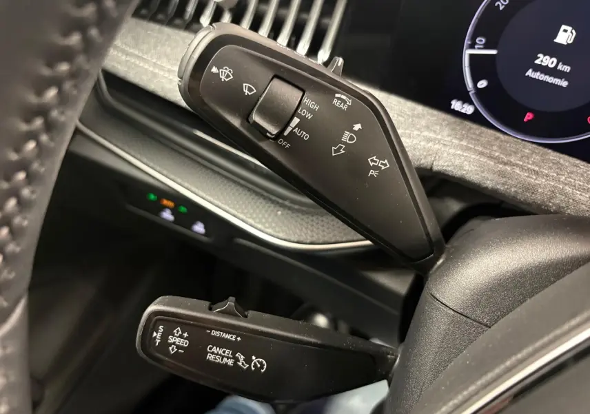 Détail intérieur du volant côté gauche du Skoda Superb Combi gris argent 2025, avec commandes de feux et régulateur.
