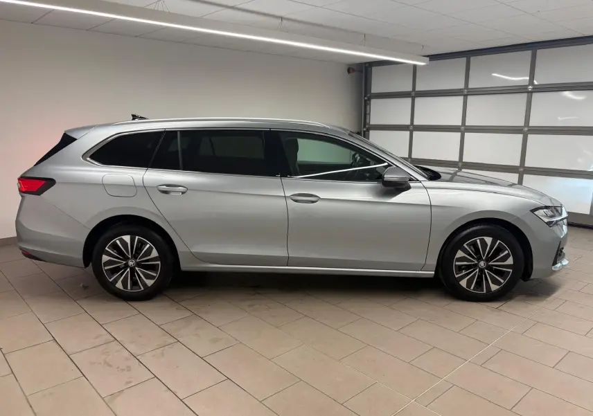 Vue latérale droite d'une Skoda Superb Combi gris argent 2025 dans un garage, avec jantes alliage distinctives.