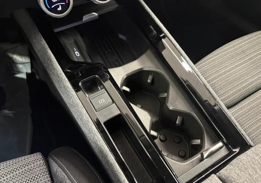 Gros plan sur la console centrale noire et grise du Skoda Superb Combi 2025, avec porte-gobelets et bouton frein à main électrique.