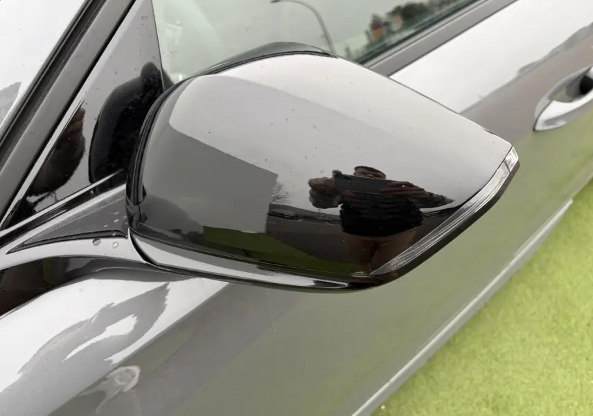 Rétroviseur extérieur droit noir brillant sur Peugeot 308 gris selenium, vue rapprochée côté conducteur.