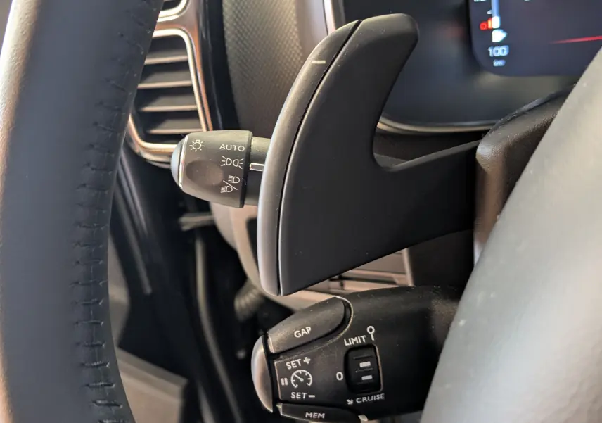 Gros plan sur les commandes au volant côté gauche d’un Citroën C5 Aircross noir, avec palettes de changement de vitesse et régulateur.