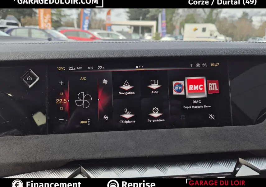 Vue rapprochée de l'écran tactile central du tableau de bord du DS4 beige, affichant la climatisation et la radio RMC.